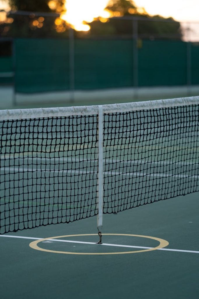 A tennis net on a court at sunset, perfect for sports themes.