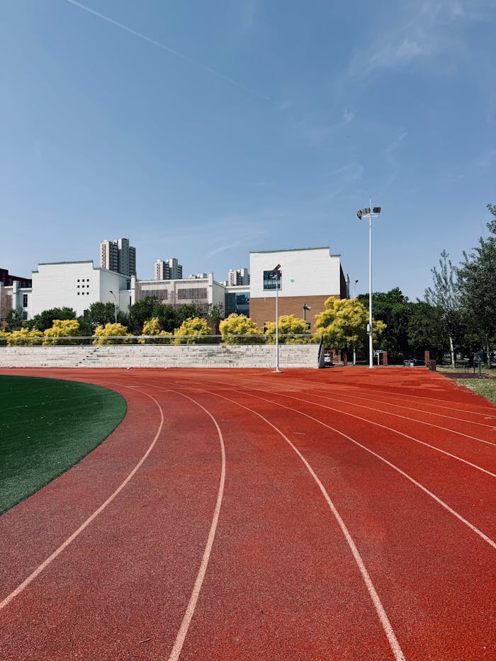 A clean, vibrant running track with city skyline in the background under a clear sky.