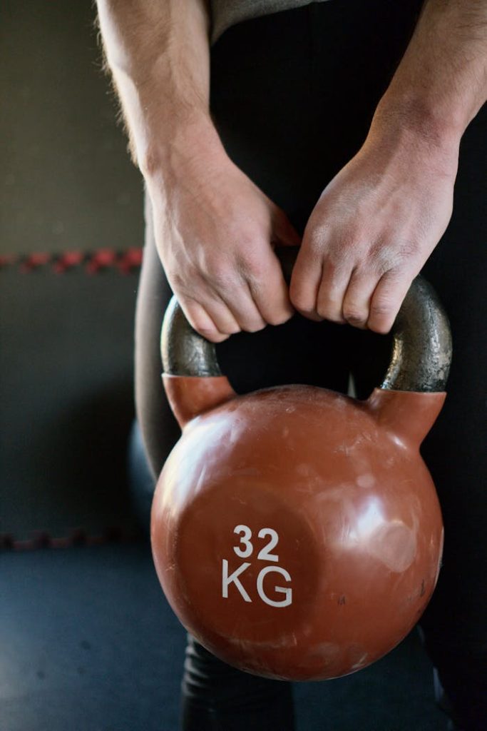 Close-up of hands holding a 32 kg kettlebell during a gym workout.