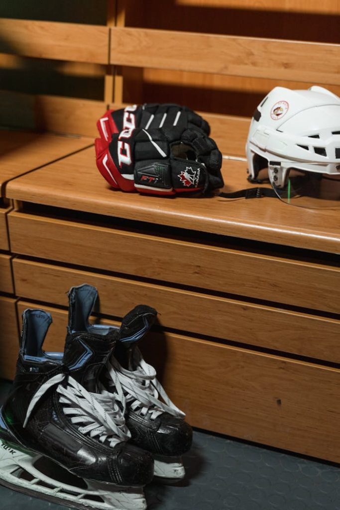 Hockey helmet, skates, and gloves on wooden bench in locker room.