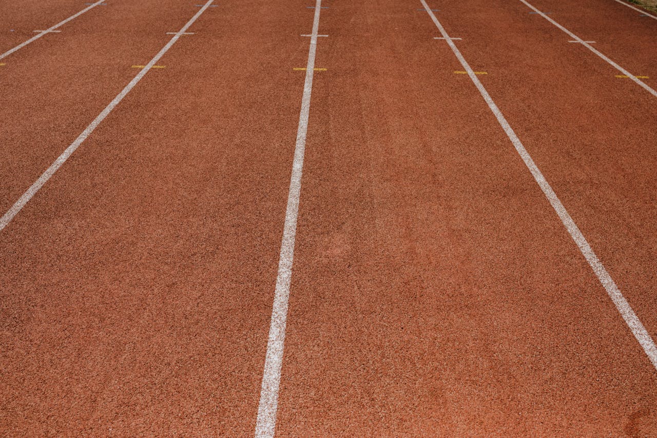 Empty red running track with marked lanes, ready for athletes.